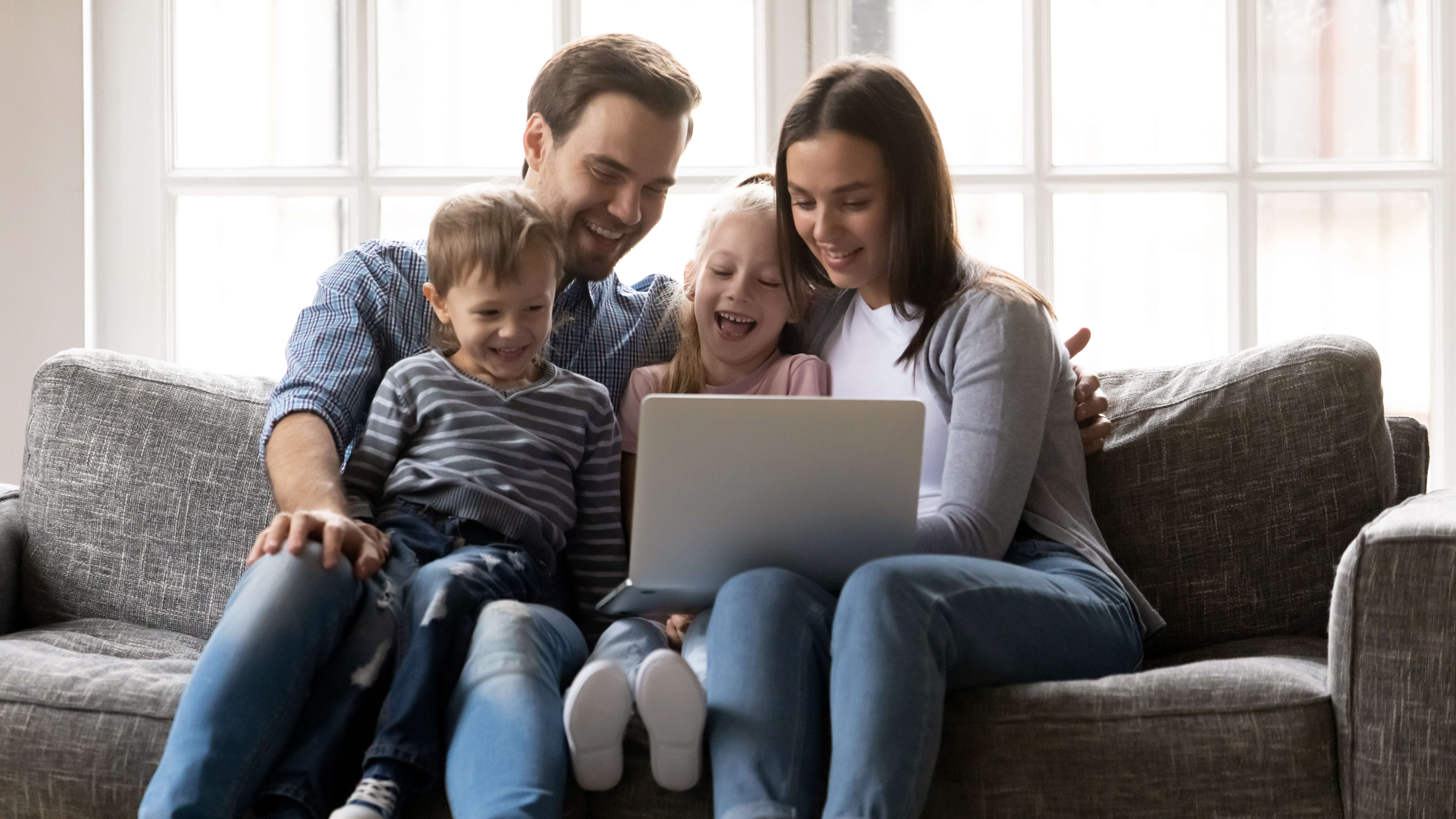 En familj på fyra personer som tittar på en dator tillsammans